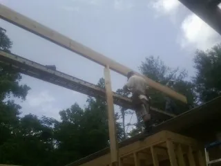 Carpenter setting a ridge beam over a new addition frame — Ice Dam Removal by Roofing Brothers in Florida