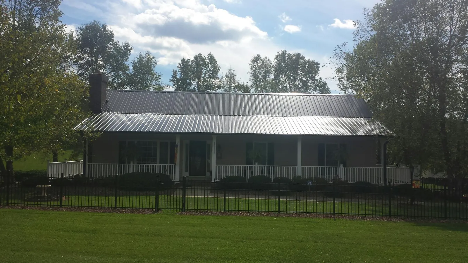 Gray metal roof on a brick ranch with a full width front porch — Gutter Guard Installation work by our crew in Florida