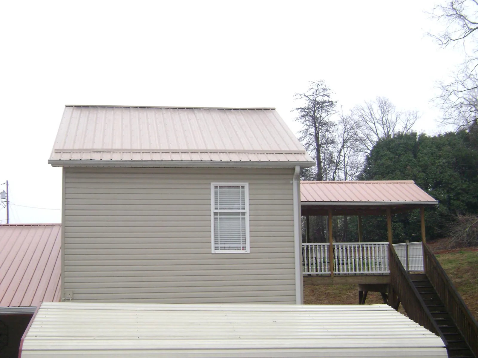 Tan metal roofs on a two story addition and attached porch, from a Roof Replacement job in Florida