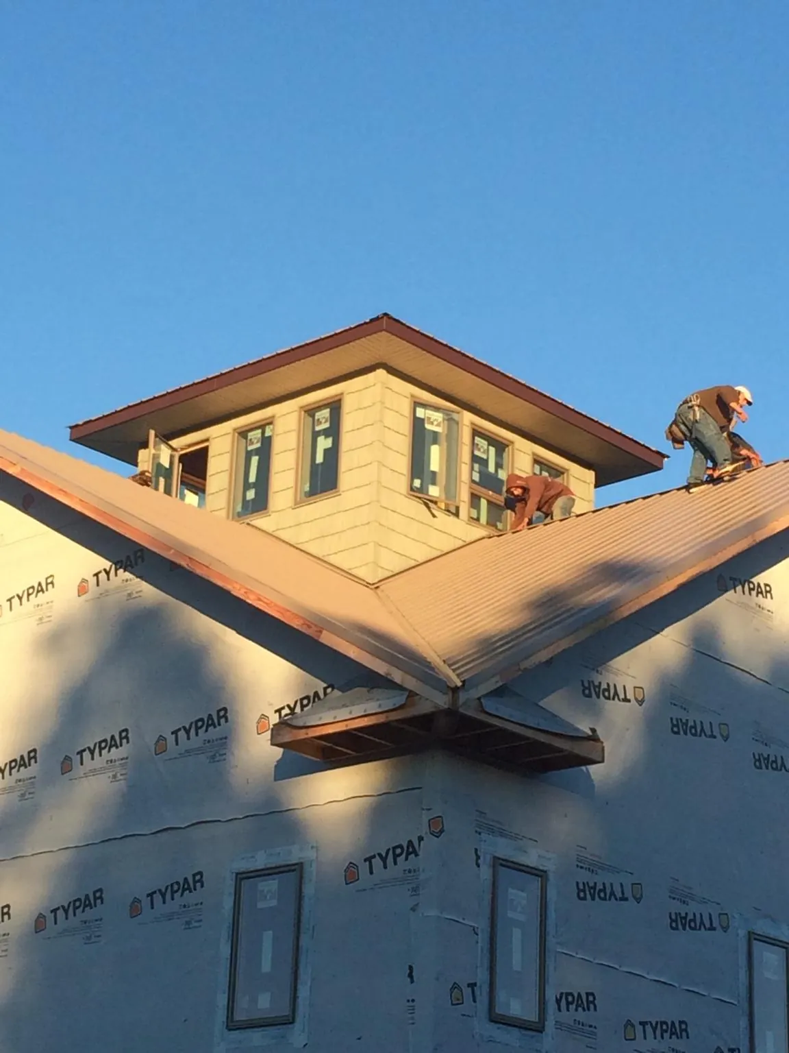 Roofers working around a rooftop cupola on a new metal roof at sunset — Roof Waterproofing in Florida by Roofing Brothers